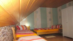 A room with two beds, a stone wall, and a wooden ceiling. - Holiday apartment with 3 bedrooms (Marsberg)