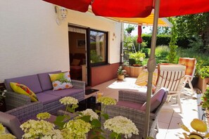 An outdoor patio with wicker furniture, a sofa, and a dining table. - Holiday apartment Sunflower with sauna and garden (Daun)