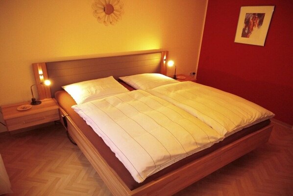 A double bed with a wooden headboard and two bedside lamps. - Holiday apartment Sunflower with sauna and garden (Daun)