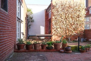 A brick building with a small patio area, a wooden table, and various potted plants. - Holiday apartment in Tangermünde with Wi-Fi (Tangermünde)