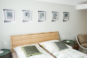 A bedroom with a bed, pillows, a chair, a nightstand, and framed pictures on the wall. - Holiday apartment in Tangermünde with Wi-Fi (Tangermünde)