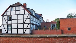 Een klassiek vakantiehuis met vakwerk, een bakstenen uitbouw, een duidelijke schoorsteen en een geplaveid terras.