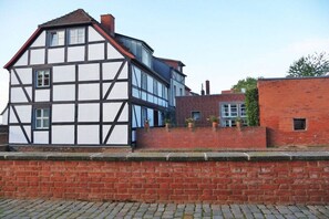 A traditional half-timbered house with a brick extension, a visible chimney, and a paved front area. - Holiday apartment in Tangermünde with Wi-Fi (Tangermünde)