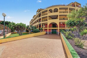 A multi-story hotel with a central courtyard, balconies, and a variety of plants.