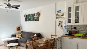 A compact living space with a dining area, kitchenette, and a ceiling fan. - Holiday Apartment 'Casa Cactus Tenerife' with Pool, Teide Views, and Air Conditioning (Arona)