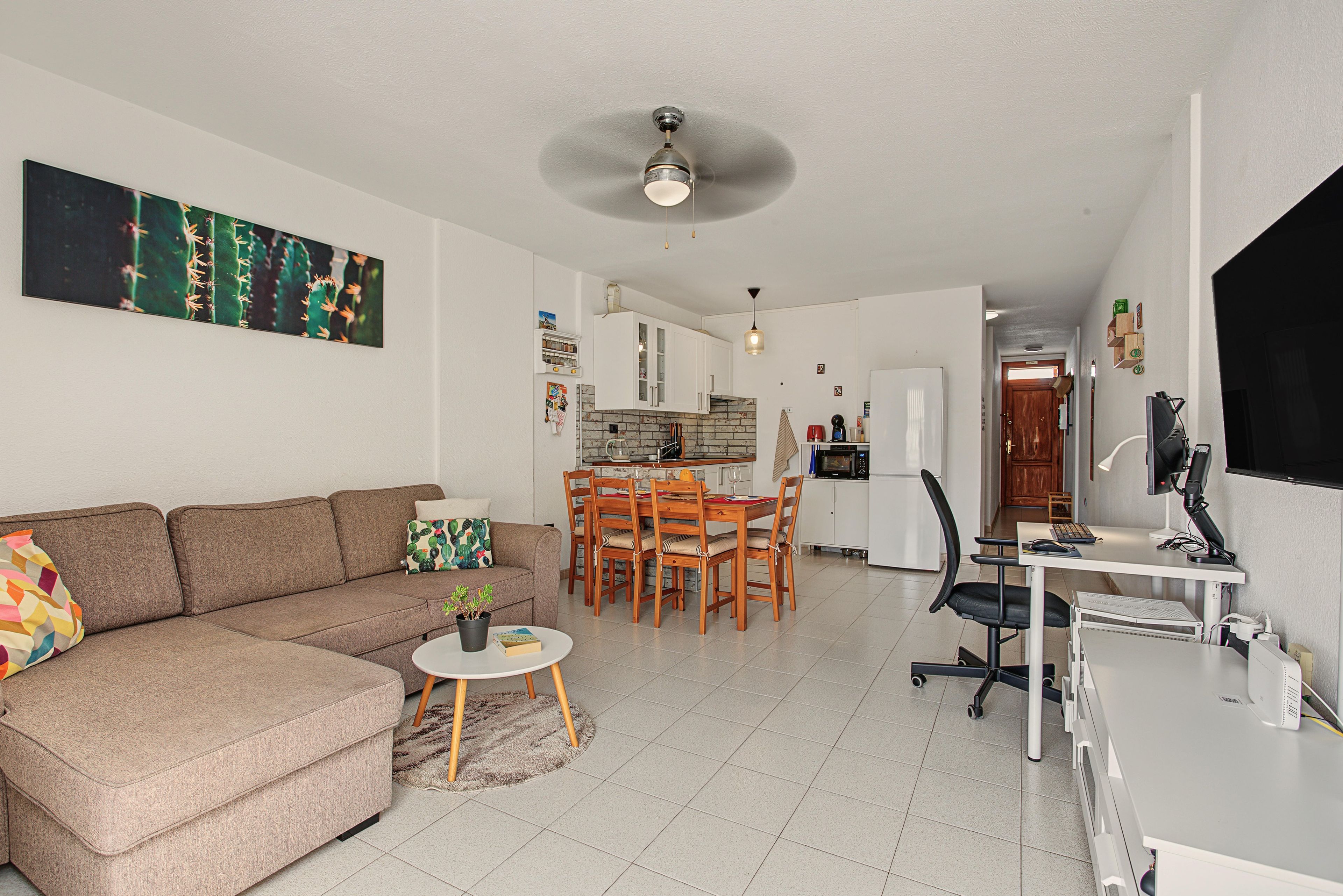 A modern living room with a sofa, a dining table, and a kitchen in the background.