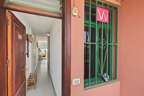 A hallway with a wooden door, a window with green shutters, and a sign indicating a vacation rental.