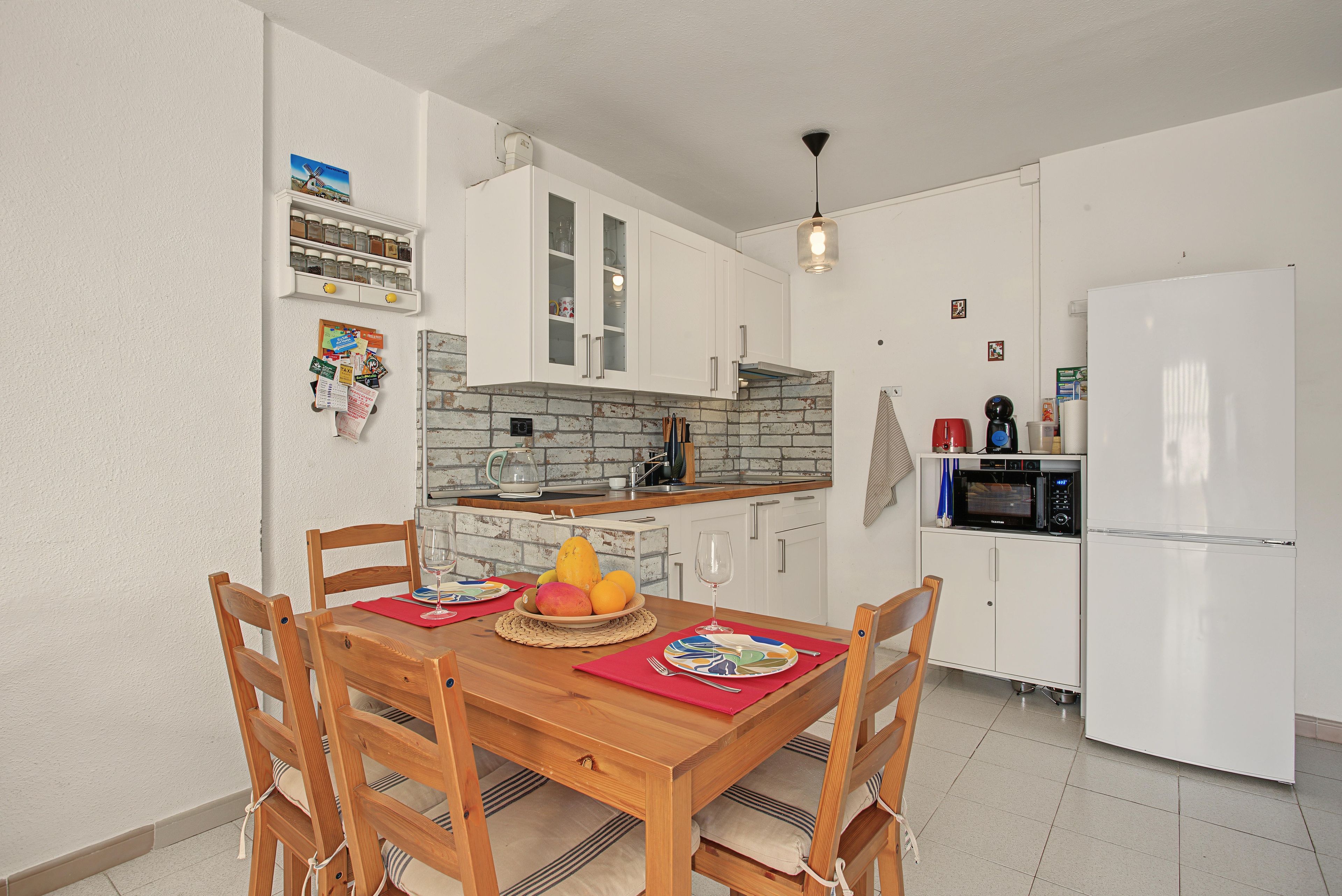 A compact kitchen with white cabinets, a brick backsplash, and a built-in microwave.
