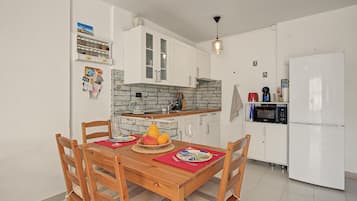 A compact kitchen with white cabinets, a brick backsplash, and a built-in microwave.