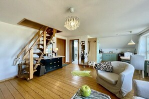 A spacious living area with a staircase, a dining area, and a kitchen. - Holiday apartment with 1 bedroom (Dornumersiel)