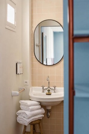 Ein Badezimmer mit Waschbecken, Spiegel und gestapelten Handtüchern.