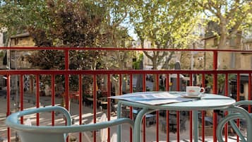 A balcony with a table and chairs, a newspaper, and a cup.