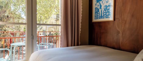 Quarto de hotel com uma cama grande, janela com cortinas e vista para o exterior.