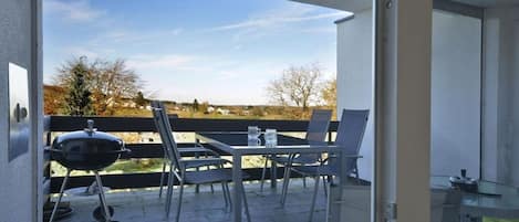 Un patio exterior con una parrilla, sillas y una mesa.