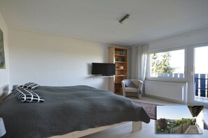 A bedroom with a bed, a television, a bookshelf, a chair, and a window. - Holiday home in Eifel with 4 bedrooms (Dockweiler)