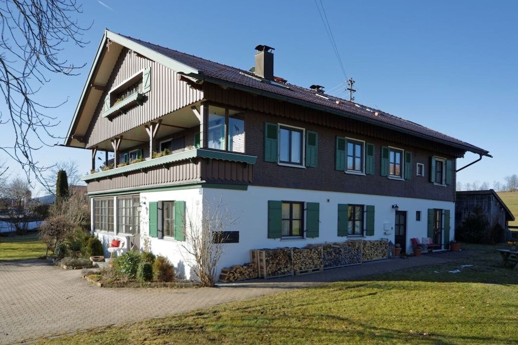 A two-story house with a balcony, a chimney, and a garden area.