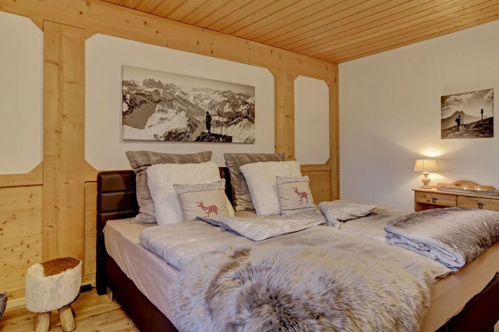 Quarto com cama grande, cabeceira de madeira e duas pinturas na parede.