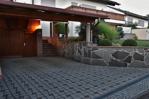 Ein Wohnhaus mit Steinmauer, Holztür und gepflastertem Eingangsbereich.