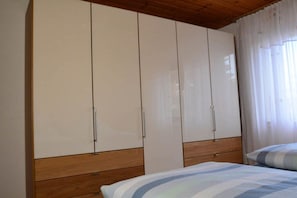 Ein Schlafzimmer mit einem Bett, einem Holzkopfseitenverkleidung und einem großen Kleiderschrank mit mehreren Türen.