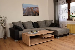 Ein modernes Wohnzimmer mit einer Eckcouch, einem Couchtisch aus Holz und einem Gemälde einer Brücke an der Wand.