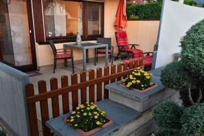 Un espace patio aménagé avec une table et des chaises, une clôture en bois et des jardinières.