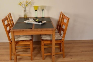 Une table à manger en bois, quatre chaises, un vase avec des fleurs jaunes et deux lampes.