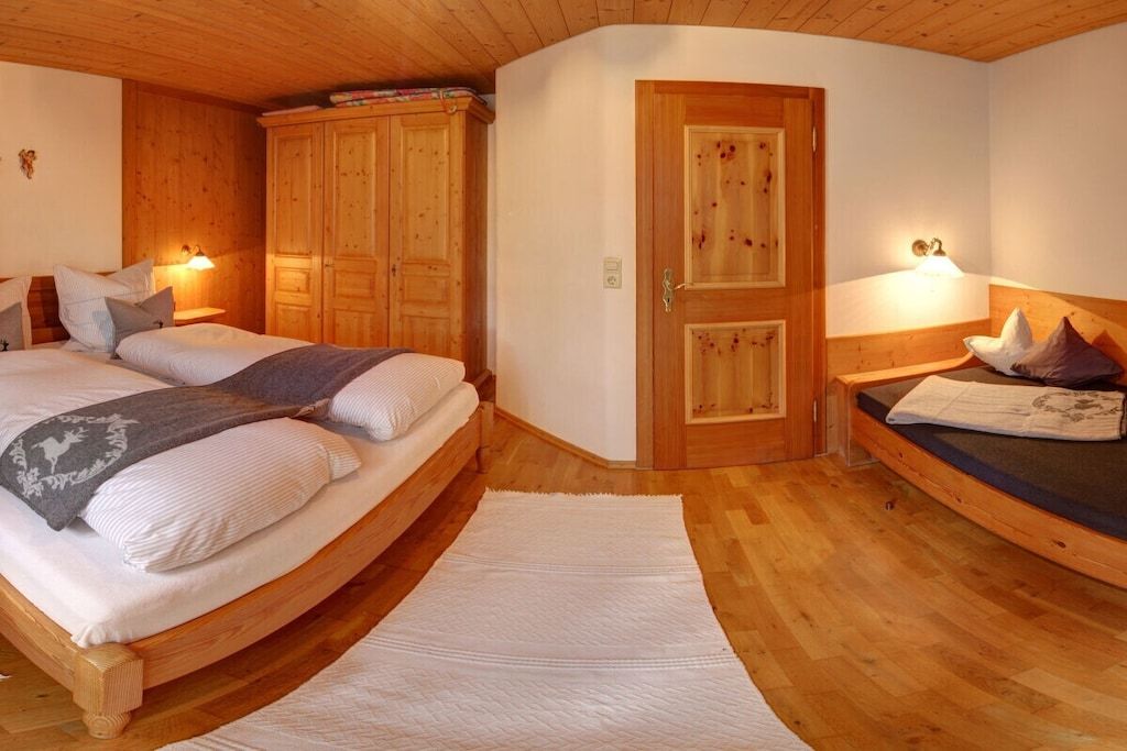 Un dormitori amb un llit de fusta, un armari i una porta.