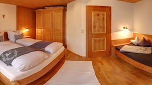 A bedroom with a wooden bed, a wardrobe, and a door. - Farmhouse with 1 bedroom (Inzell, Deutschland)