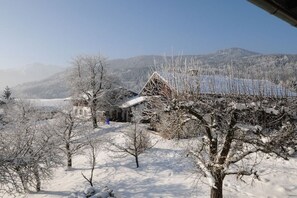 A snow-covered landscape with a building that has a sloped roof and a visible chimney.