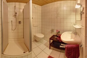 Ein Badezimmer mit Dusche, Toilette, Waschbecken und einer kleinen Ablage mit einem Handtuch.