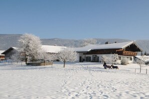 A snow-covered landscape with a wooden building and a clear sky.