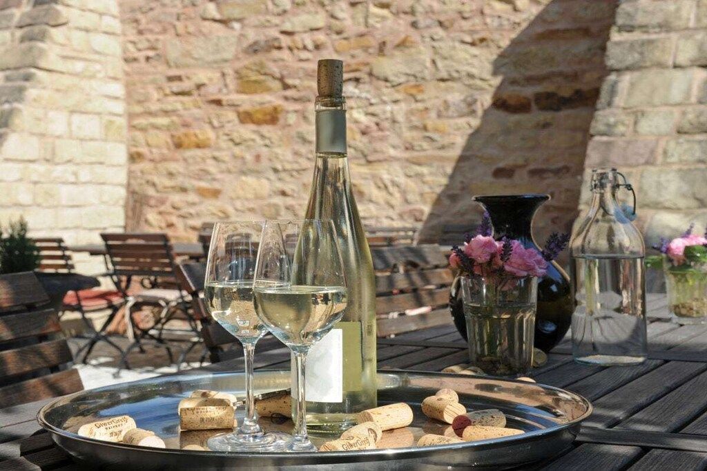 Une table avec une bouteille, des verres et des bouchons disposés sur un plateau, le tout placé devant un mur de pierre.