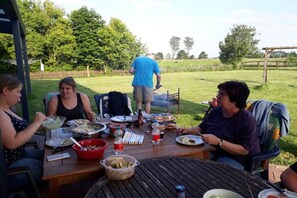 Ein Essbereich im Freien mit einem runden Tisch, Stühlen und einer Person im Hintergrund.