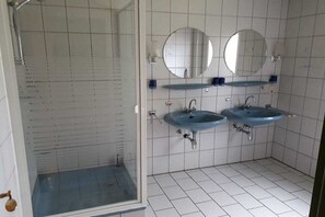 Ein Badezimmer mit zwei Waschbecken, zwei Spiegeln und einer Duschkabine.