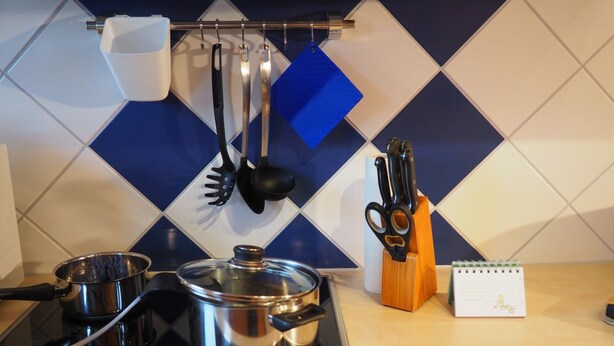 Cozinha com fogão, panelas, um calendário e utensílios de cozinha.