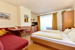 A hotel room with a bed, a desk, a chair, a wardrobe, and a window with curtains. - Holiday apartment with 1 bedroom (Grainau)