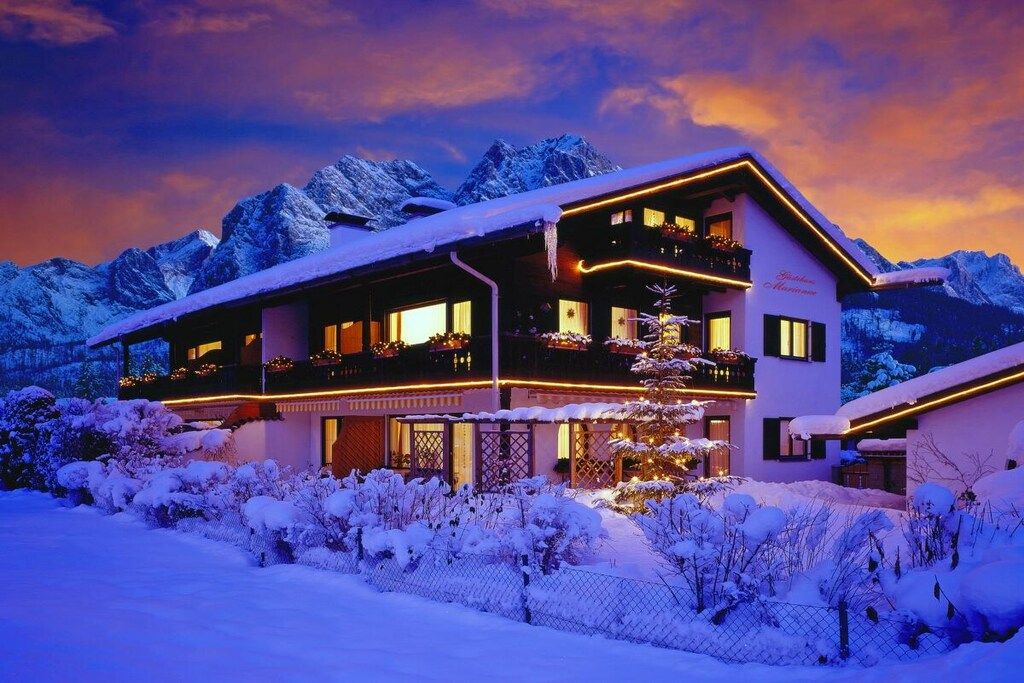 Hotel de dos pisos con balcones, rodeado de montañas nevadas.