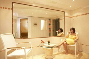A bathroom with a large mirror, a glass-topped sink, a chair, and a shower area. - Holiday apartment with 1 bedroom (Grainau)