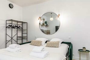 A hotel room with a bed, a wardrobe, a mirror, and a small table. - Charming studio - 2P - Voltaire (Paris)