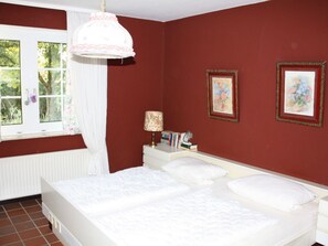 A bedroom with a double bed, a bedside table with a lamp, and two framed pictures on the wall. - Holiday Apartment With 1 Bedroom (Krummhoern)