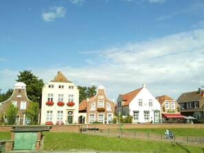 A row of traditional European-style buildings with distinct architectural features, a grassy area in the foreground, and a clear sky. - Holiday Apartment With 1 Bedroom (Krummhoern)