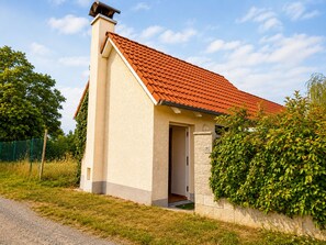 A single-story house with a red-tiled roof, a chimney, and a door leading to the entrance.
