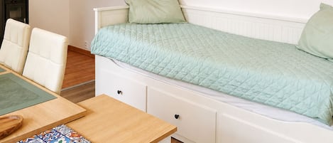 A bedroom with a bed, a bedside table, a chair, and a wall-mounted artwork.