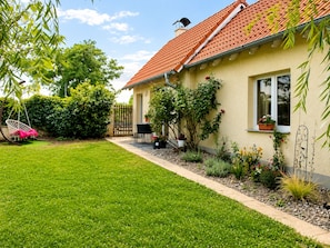 A house with a red-tiled roof, a well-maintained lawn, and a swing chair.