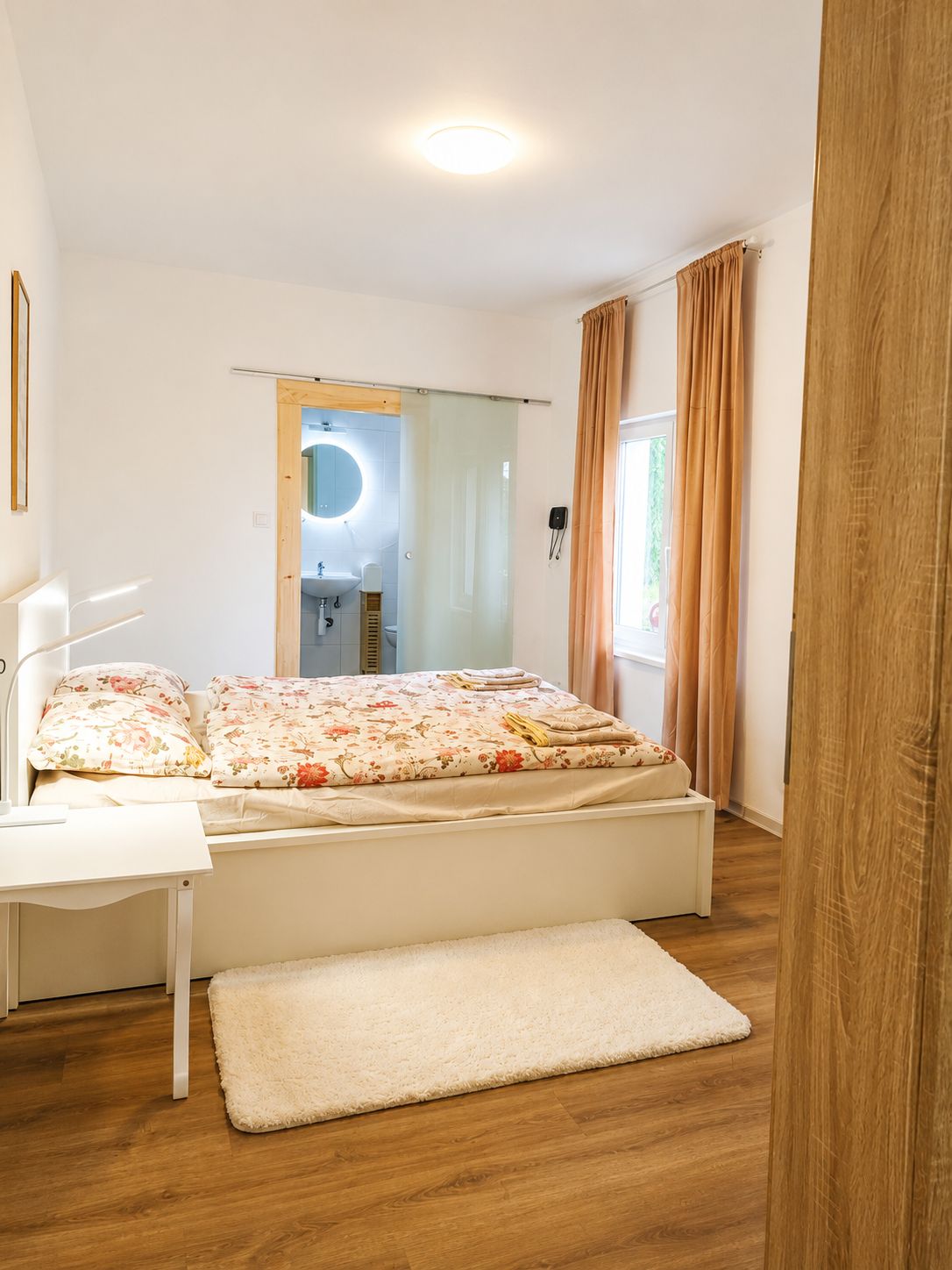 Ein Schlafzimmer mit einem Bett, einem Nachttisch und einem Fenster mit Vorhängen.
