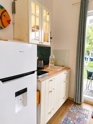 A compact kitchen with a white refrigerator, a coffee maker, and a sink.