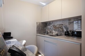 A modern kitchen with a marble backsplash, a built-in stove, and a coffee maker. - Nouar (Athina)