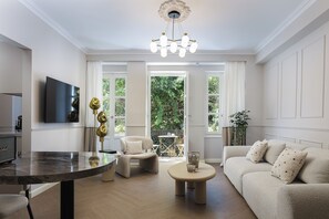 A living room with a sofa, a coffee table, a TV, and a dining area with a table and chairs. - Nouar (Athina)