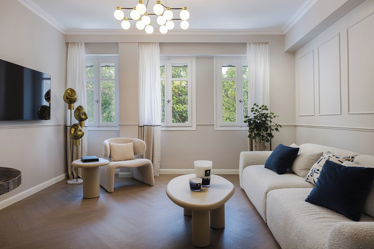 A modern living room with a sofa, armchair, coffee table, and a flat-screen TV.