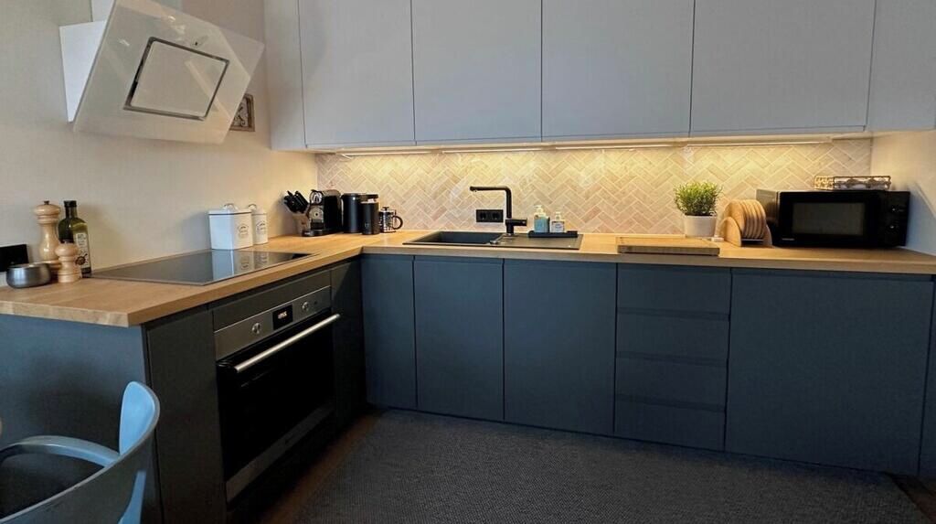 Een kleine keuken met een inbouwoven, een magnetron en een spoelbak.